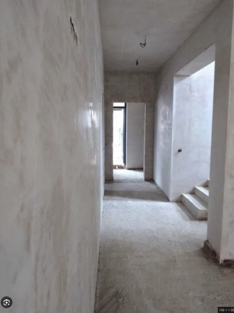 Checking a plastered wall for flatness using a long straightedge