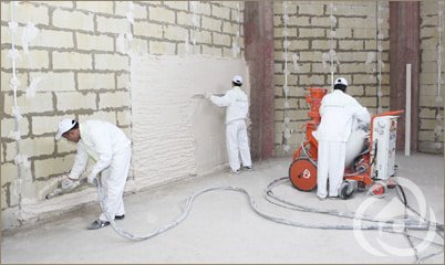 Two plasterers working on internal walls beside a plastering machine
