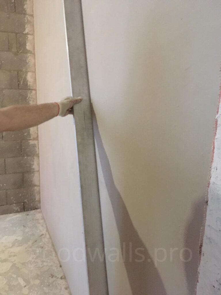 Plasterer levelling fresh plaster on an internal wall with a straightedge